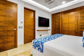 A bedroom with a bed, wooden wardrobes, a mounted TV, and a built-in shelf. - Exceptional Waterfront Condo With Pool, Balcony, Fitness Area, & W/D (Puerto Vallarta)