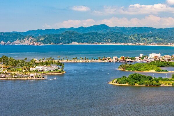A coastal cityscape with a marina, buildings, and a mountainous backdrop.