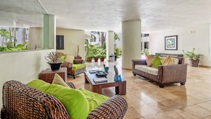 Un espacio interior amplio con muebles de mimbre, una mesa de centro y plantas en macetas.