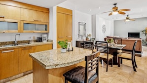 Una cocina moderna con encimeras de granito, armarios de madera y una zona de comedor con mesa y sillas.