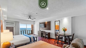 Une chambre d’hôtel équipée d’un lit, d’un bureau, d’une chaise, d’une table à manger, d’une télévision et d’un balcon avec vue.