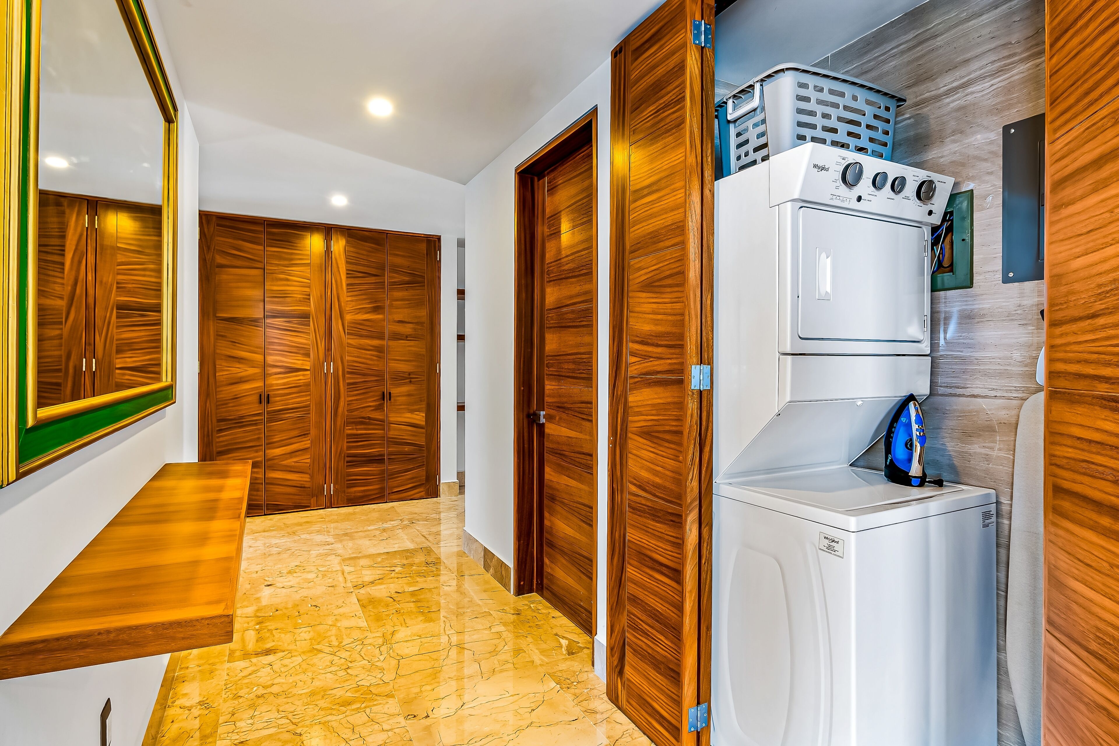 Un pasillo con puertas de madera, una lavadora y una cesta de ropa.