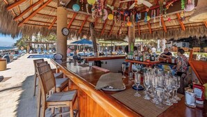 Eine Bar mit Holzmöbeln, einem Pool und einem Reetdach.
