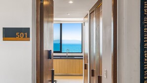 Un pasillo con vista al mar a través de una ventana, un cartel con el número 501 y puertas de madera.
