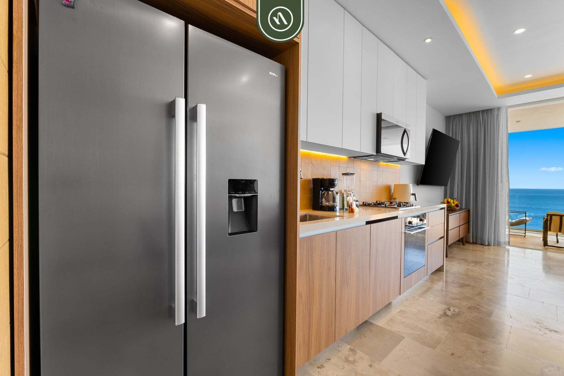 A modern kitchen with a built-in refrigerator, a stove, and a flat-screen TV.