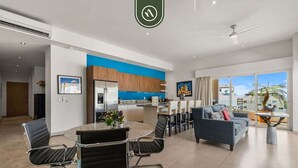 A modern living room with a sofa and a dining area with a round table and chairs. - Amazing 2 BR Condo in Romantic Zone - Rooftop Pool (Puerto Vallarta)