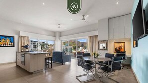 A spacious kitchen with a central island, a dining area with modern chairs, and a large window offering a view of the outdoors. - Amazing 2 BR Condo in Romantic Zone - Rooftop Pool (Puerto Vallarta)