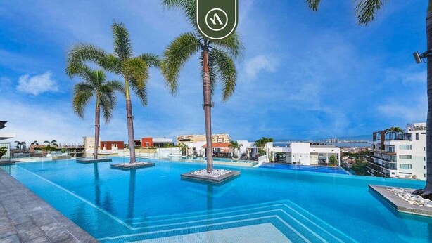 A swimming pool with palm trees and a clear sky. - Amazing 2 BR Condo in Romantic Zone - Rooftop Pool (Puerto Vallarta)