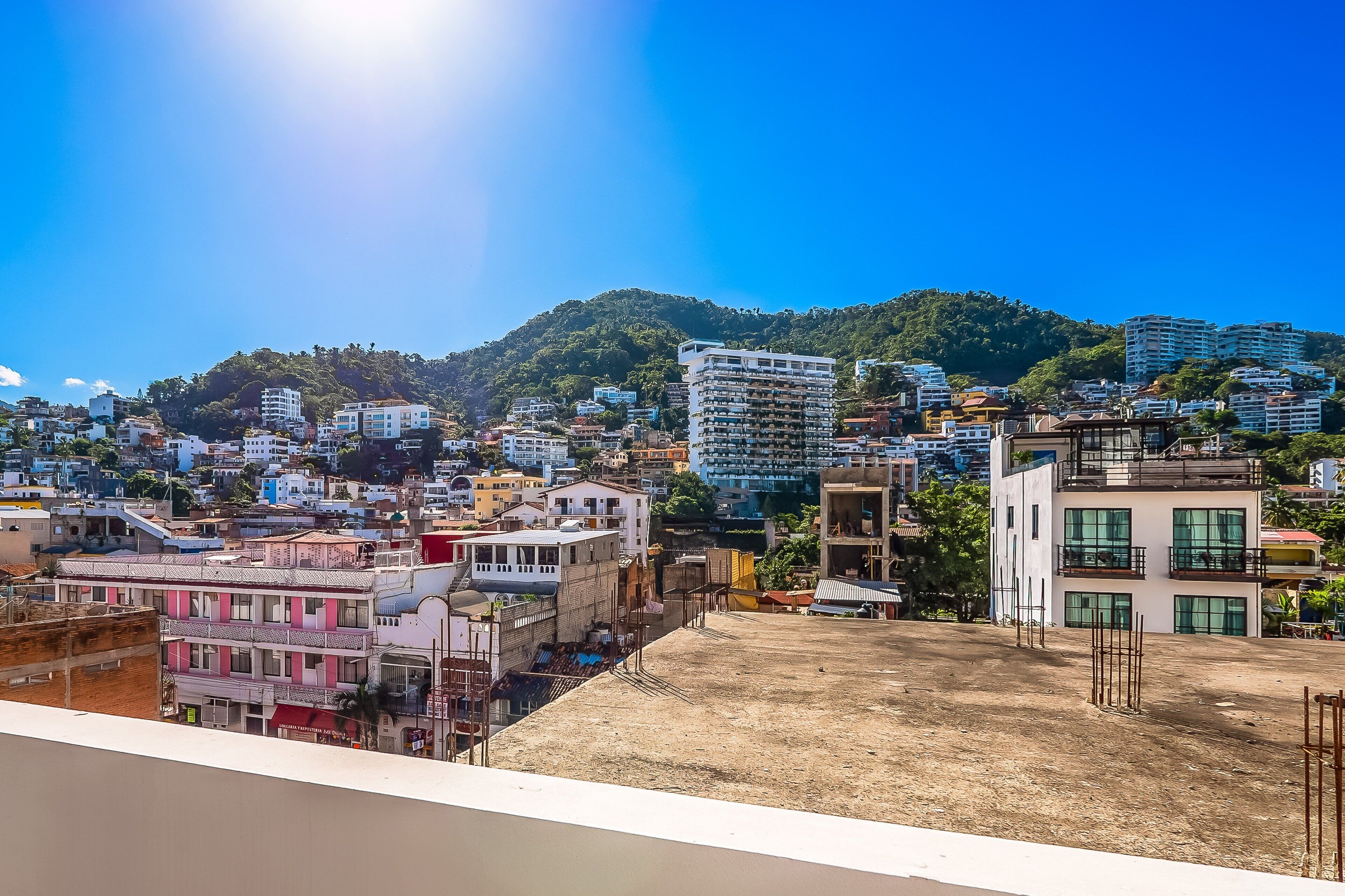 A cityscape with buildings, a hill, and a clear sky.
