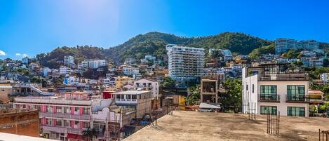A cityscape with buildings, a hill, and a clear sky.