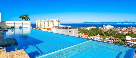 A rooftop infinity pool with a clear view of the city and the sea.