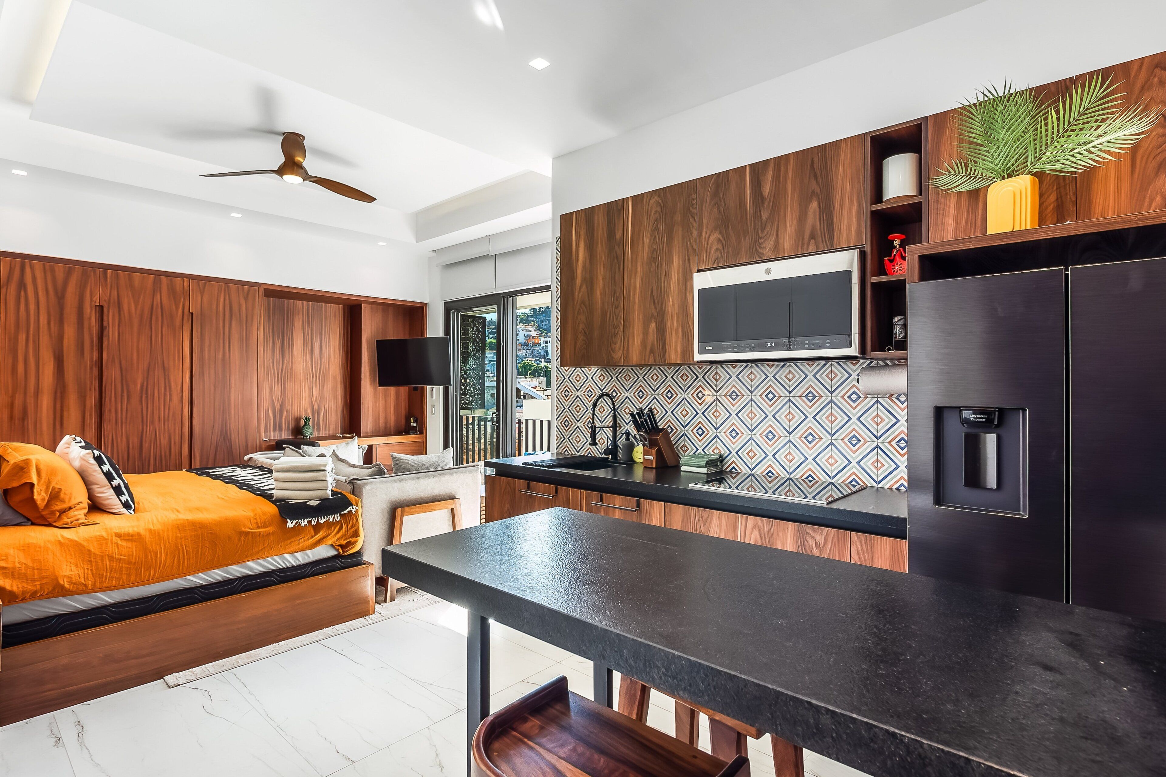A modern kitchen with a built-in microwave, a coffee machine, and a wooden cabinet.