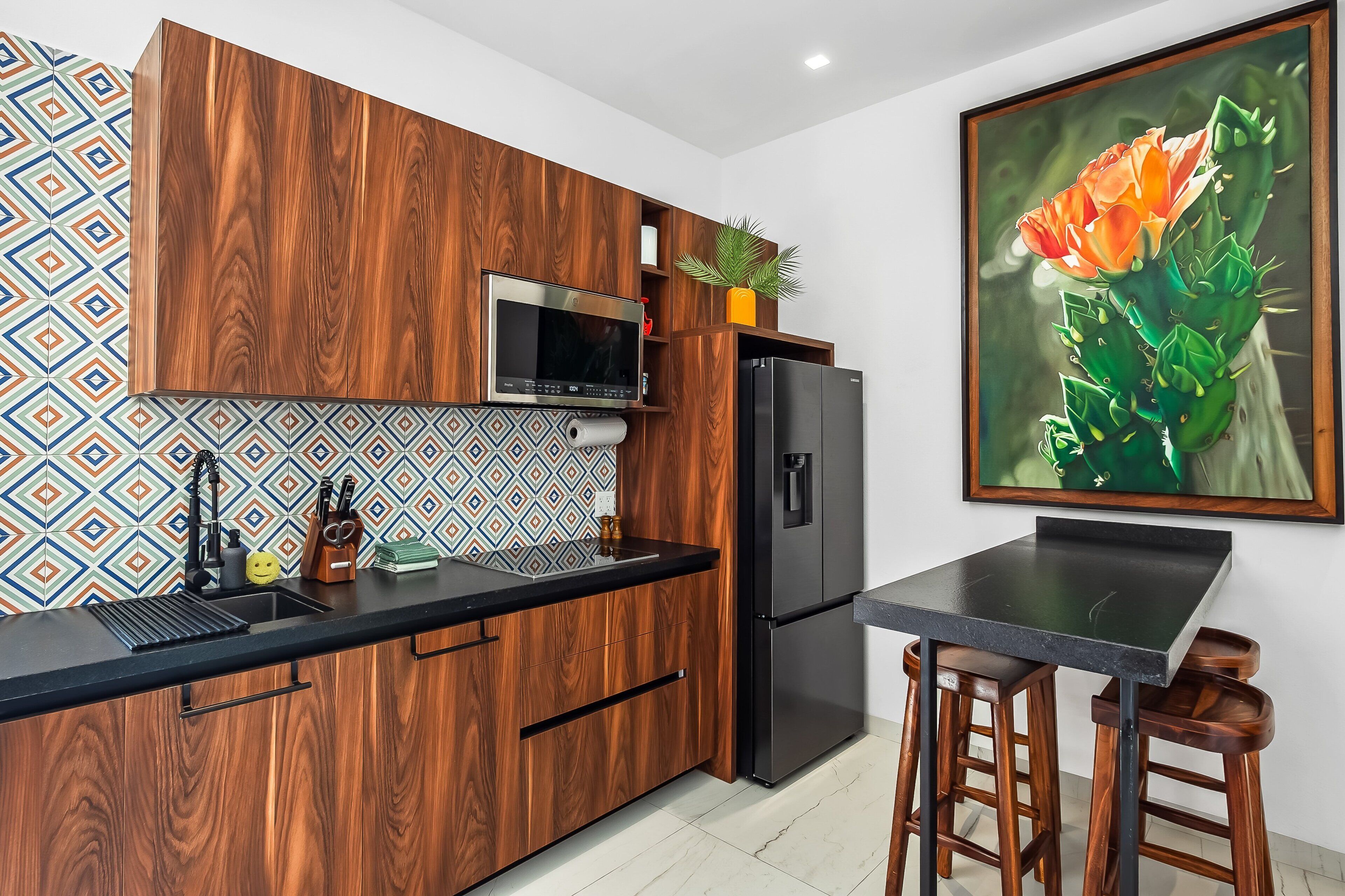 A kitchen with wooden cabinets, a stainless steel refrigerator, a microwave, and a sink.