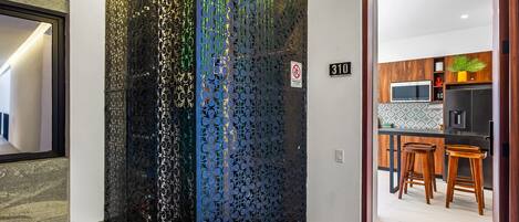 A modern interior with a decorative metal partition, a kitchen area with wooden stools, and a number sign '310' on the wall.