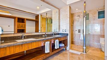 Un baño moderno con tocador de madera, lavamanos dobles, un espejo grande y ducha con cerramiento de vidrio.
