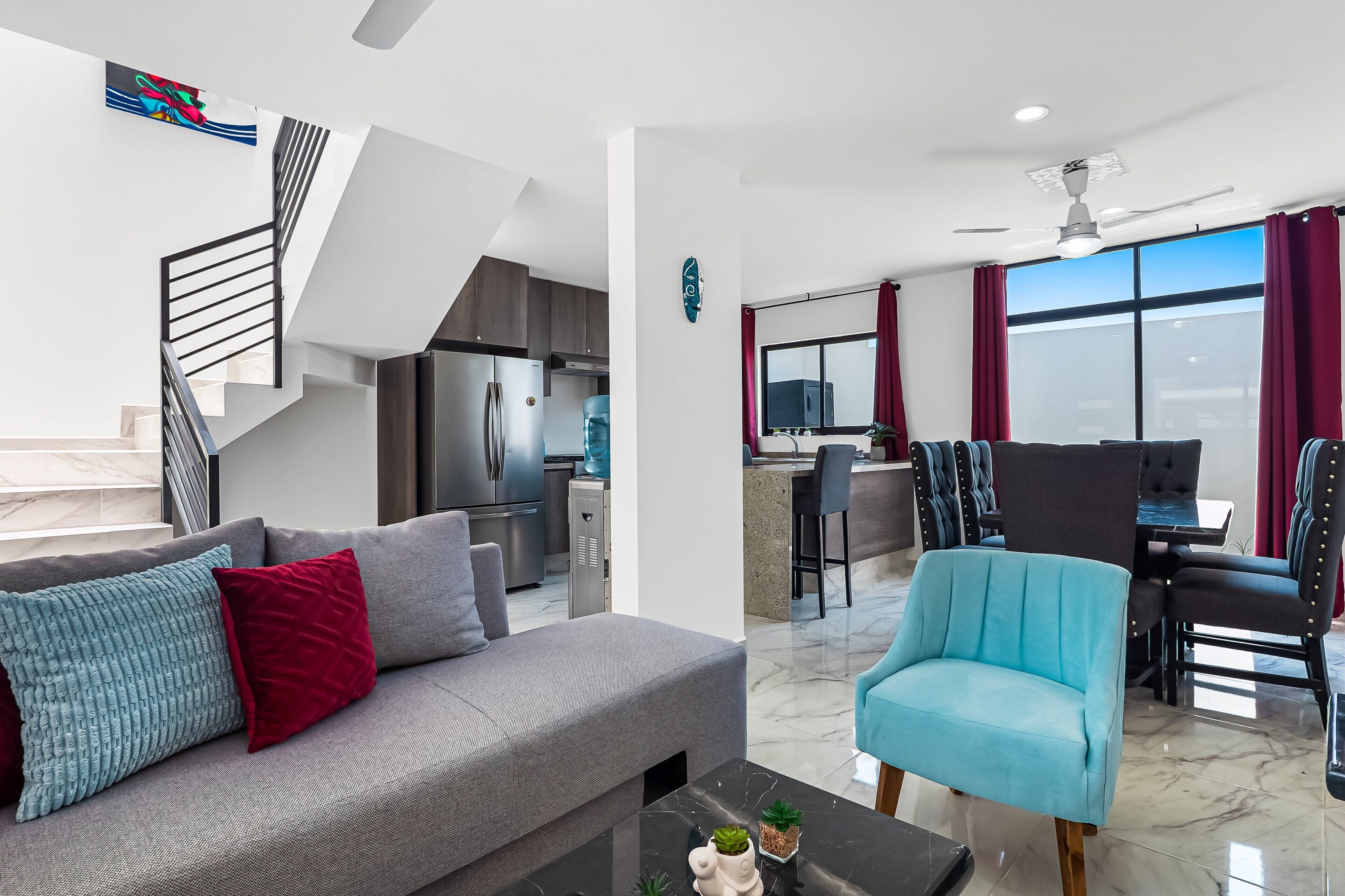 Una sala de estar moderna con un sofá gris, un sillón azul y una mesa de centro negra.