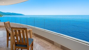 A balcony with a view of the sea and mountains, wooden furniture, and a tiled floor. - Luxurious 6th-floor Condo With Pool, Oceanfront Balcony & Water View (Puerto Vallarta)