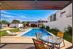 A swimming pool with lounge chairs, a glass table, and a pergola overhead. - 2-story Home Near the Beach With Outdoor Pool, Patio, Washer/dryer, Streaming (Nuevo Nayarit)