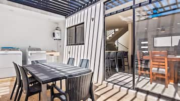 Una cocina moderna con lavadora incorporada, una zona de comedor con puerta de vidrio y una escalera que sube a un nivel superior.