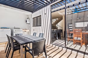 A modern kitchen with a built-in washing machine, a dining area with a table and chairs, and a glass door leading to a staircase. - 2-story Home Near the Beach With Outdoor Pool, Patio, Washer/dryer, Streaming (Nuevo Nayarit)