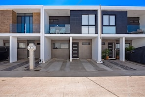 A modern multi-story residential building with balconies, a garage, and a covered outdoor seating area. - 2-story Home Near the Beach With Outdoor Pool, Patio, Washer/dryer, Streaming (Nuevo Nayarit)