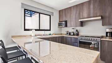 Una cocina moderna con encimera de granito, electrodomésticos de acero inoxidable y un amplio ventanal.