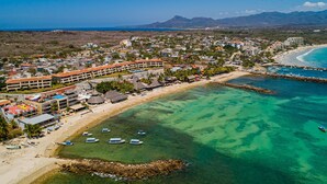 An aerial view of a coastal resort with beachfront accommodations, clear turquoise waters, and mountainous background. - Stylish Apartment Near Beach & Dining With Pool, hot Tub, Tennis, & Large Patio (Punta de Mita)