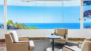 A room with a large window offering a view of the sea, two armchairs, a round table, and a patterned carpet. - Cozy Condo With Pool & AC - Family Base Near Beach & Activities, Shared hot tub (Puerto Vallarta)