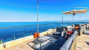 A rooftop terrace with outdoor seating, a glass balustrade, and a view of the sea. - Cozy Condo With Pool & AC - Family Base Near Beach & Activities, Shared hot tub (Puerto Vallarta)