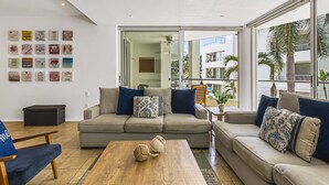 Una sala de estar moderna con un conjunto de sofás, una mesa de centro y una pared con citas motivacionales.