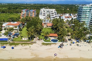 Un resort con diversi edifici, una spiaggia e palme.