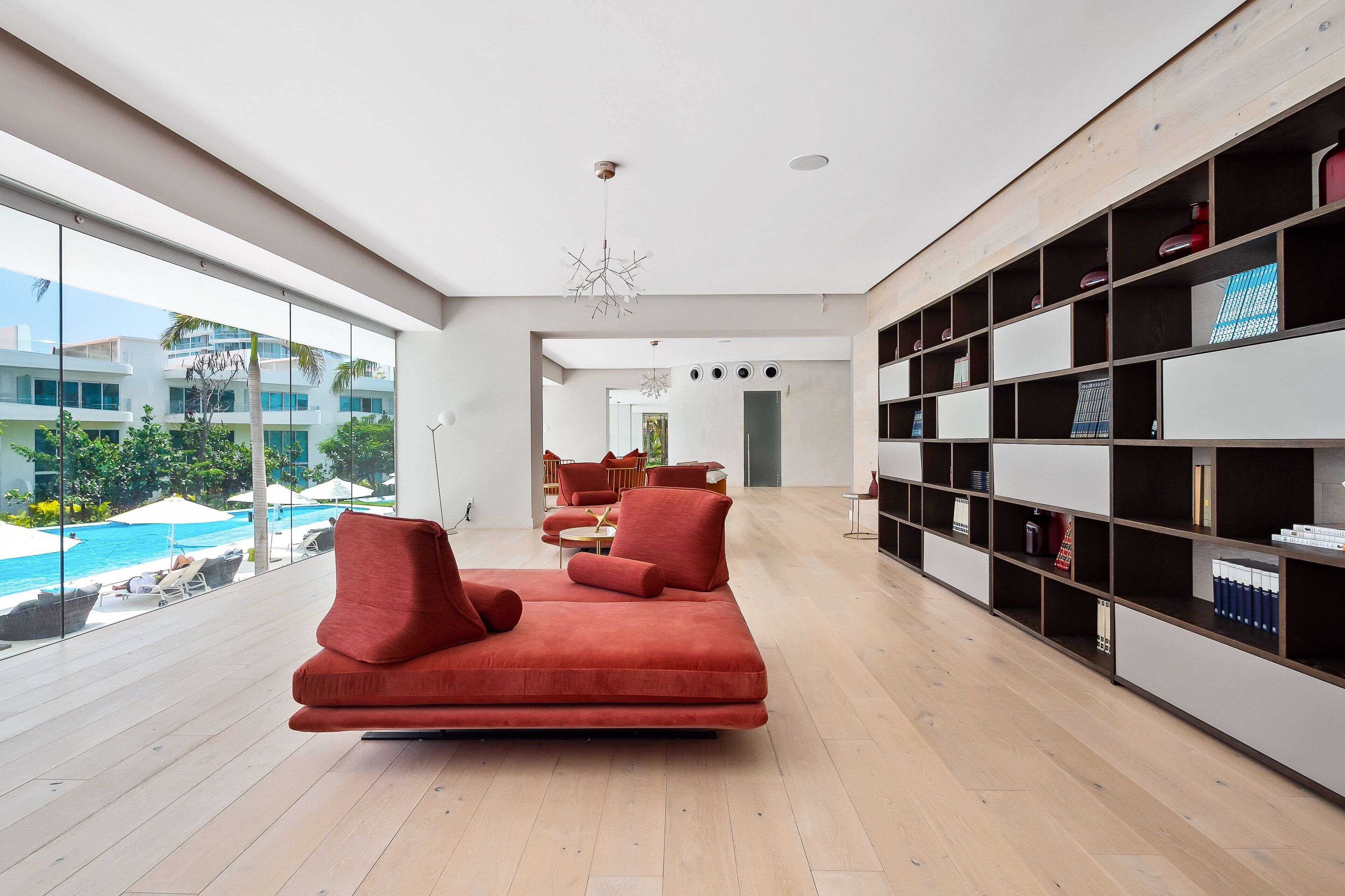 Un salon moderne avec une grande fenêtre, un canapé rouge et une bibliothèque.