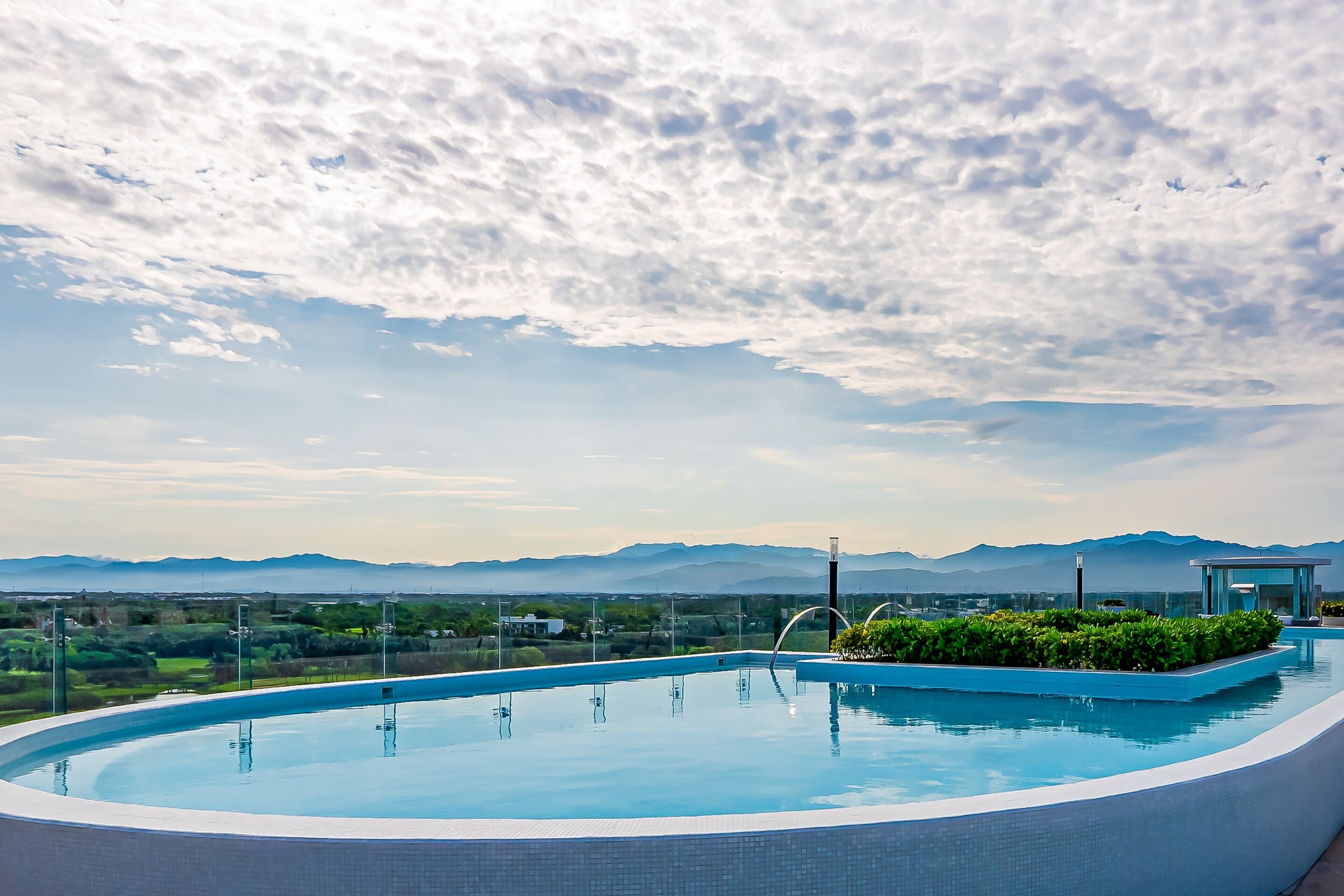 Una piscina con vistas a montañas y un cielo nublado.
