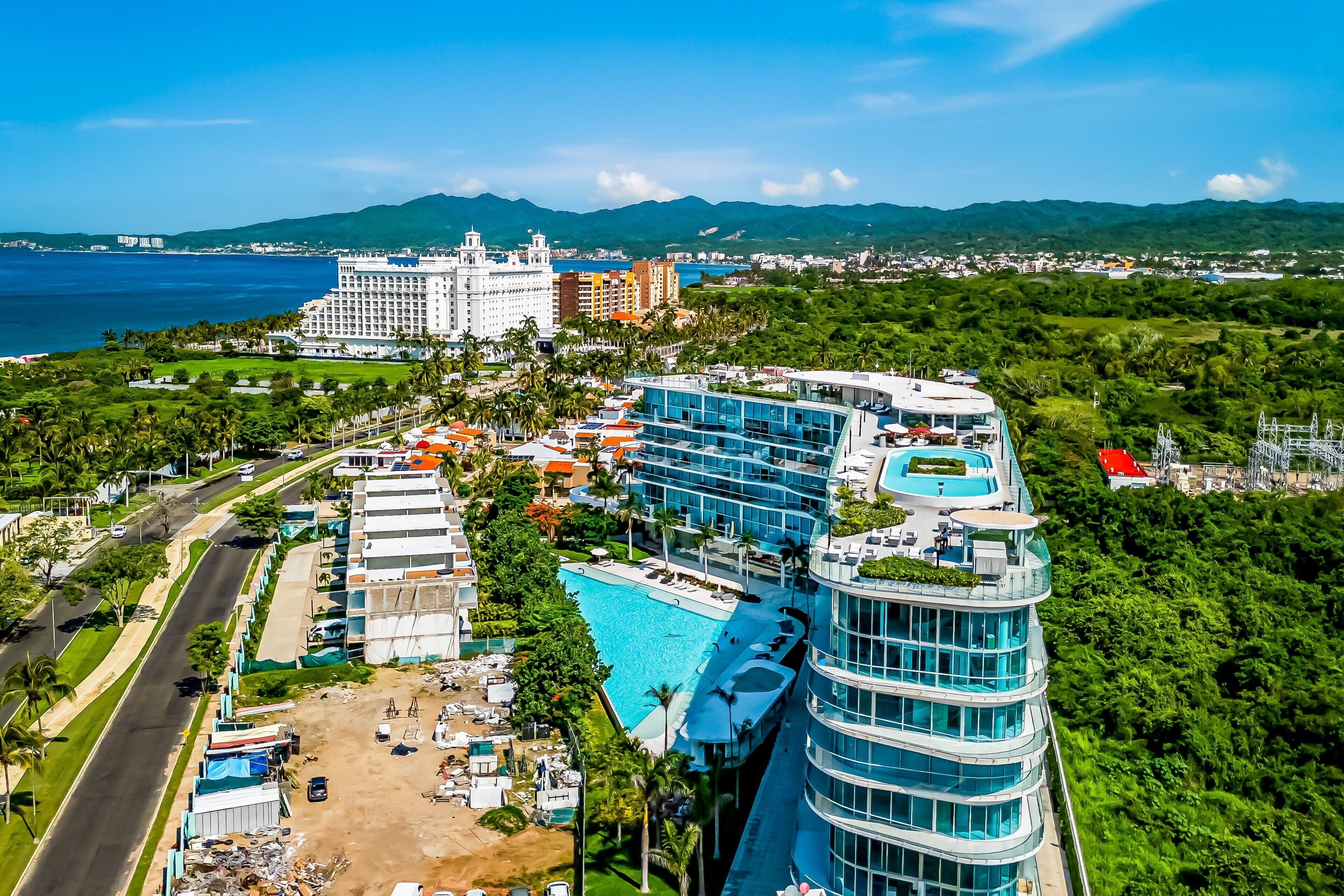 Ein Resort mit großem Pool, mehreren Gebäuden und Blick aufs Meer.