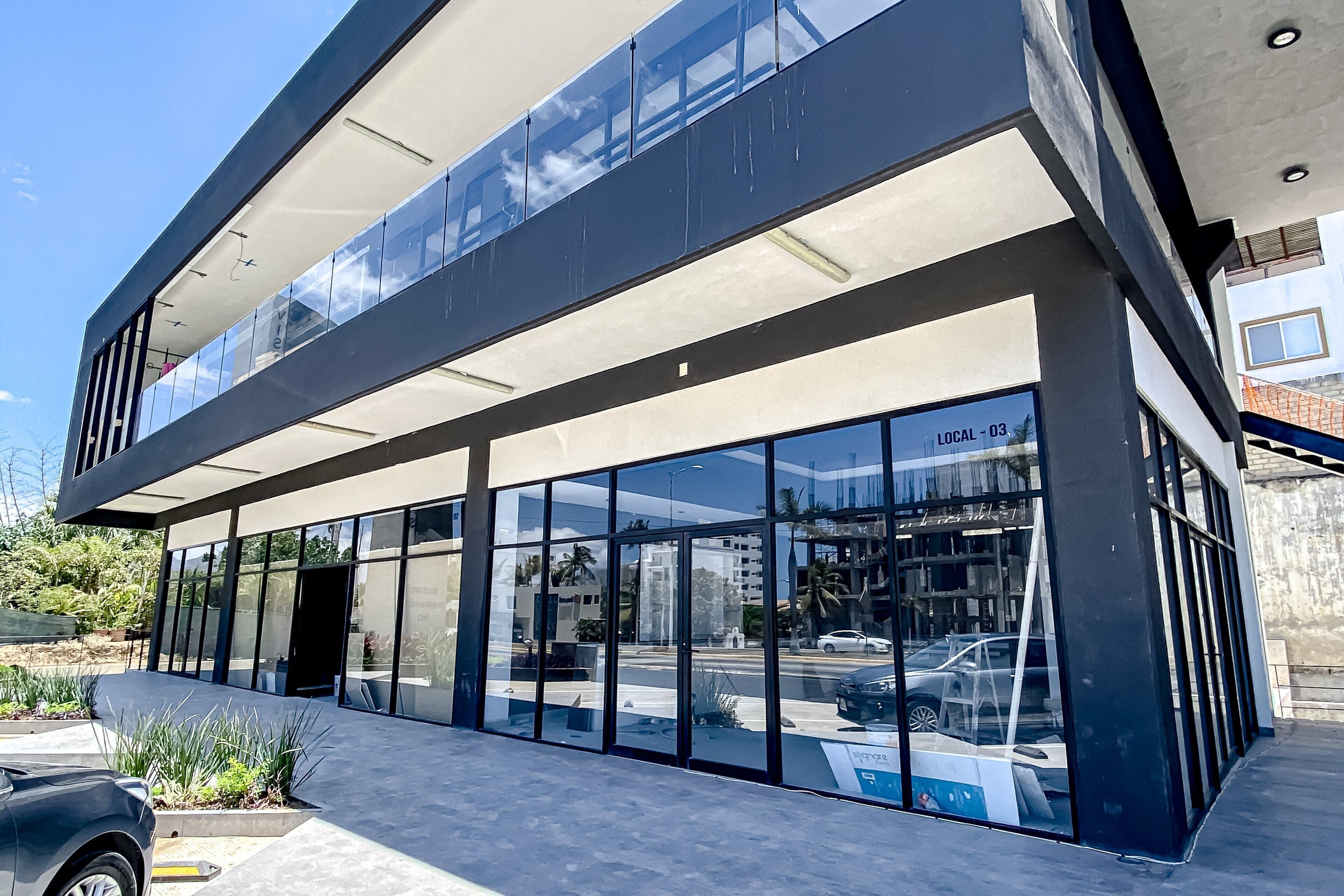 Un bâtiment moderne doté de grandes fenêtres en verre, d’un toit plat et d’une entrée bien visible.