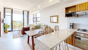 A modern kitchen with a granite countertop, wooden cabinets, and a built-in microwave. - Ocean-view Condo With Infinity Pool, Rooftop Lounge, & Private Balcony (Bucerías)