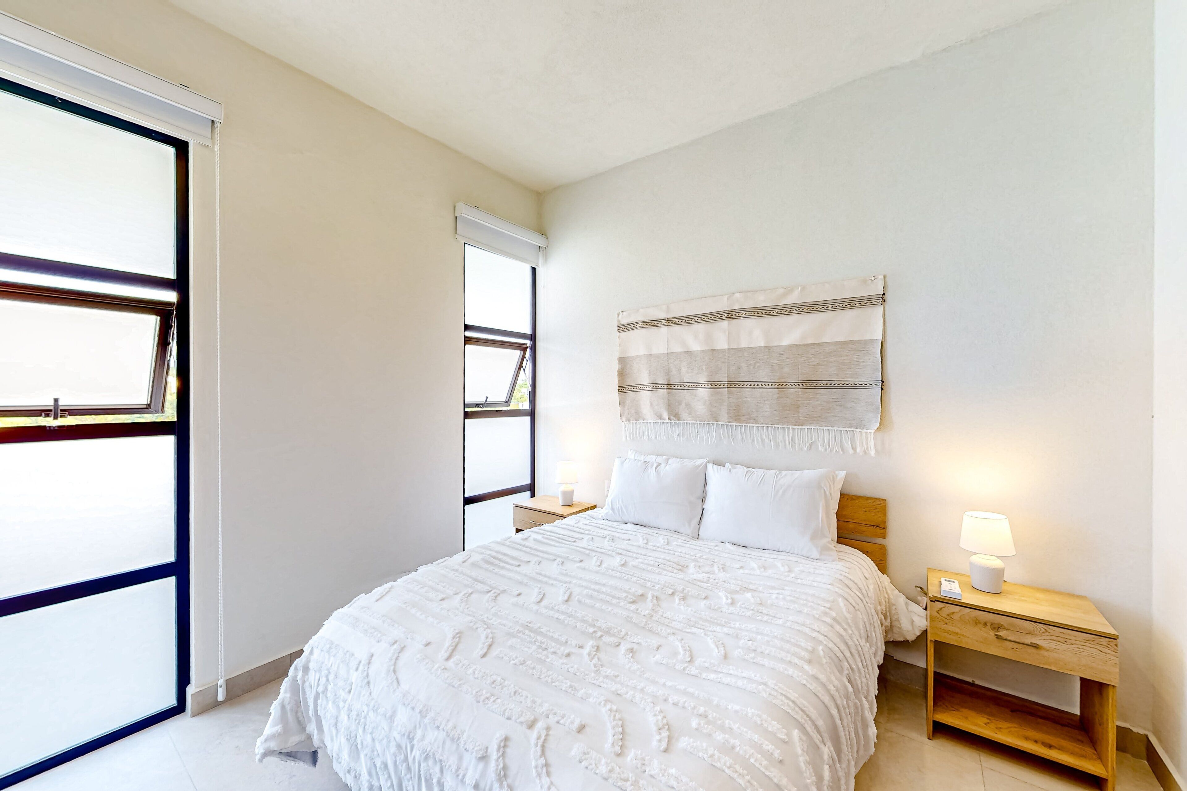 Une chambre à coucher avec un lit, une table de chevet et une fenêtre.
