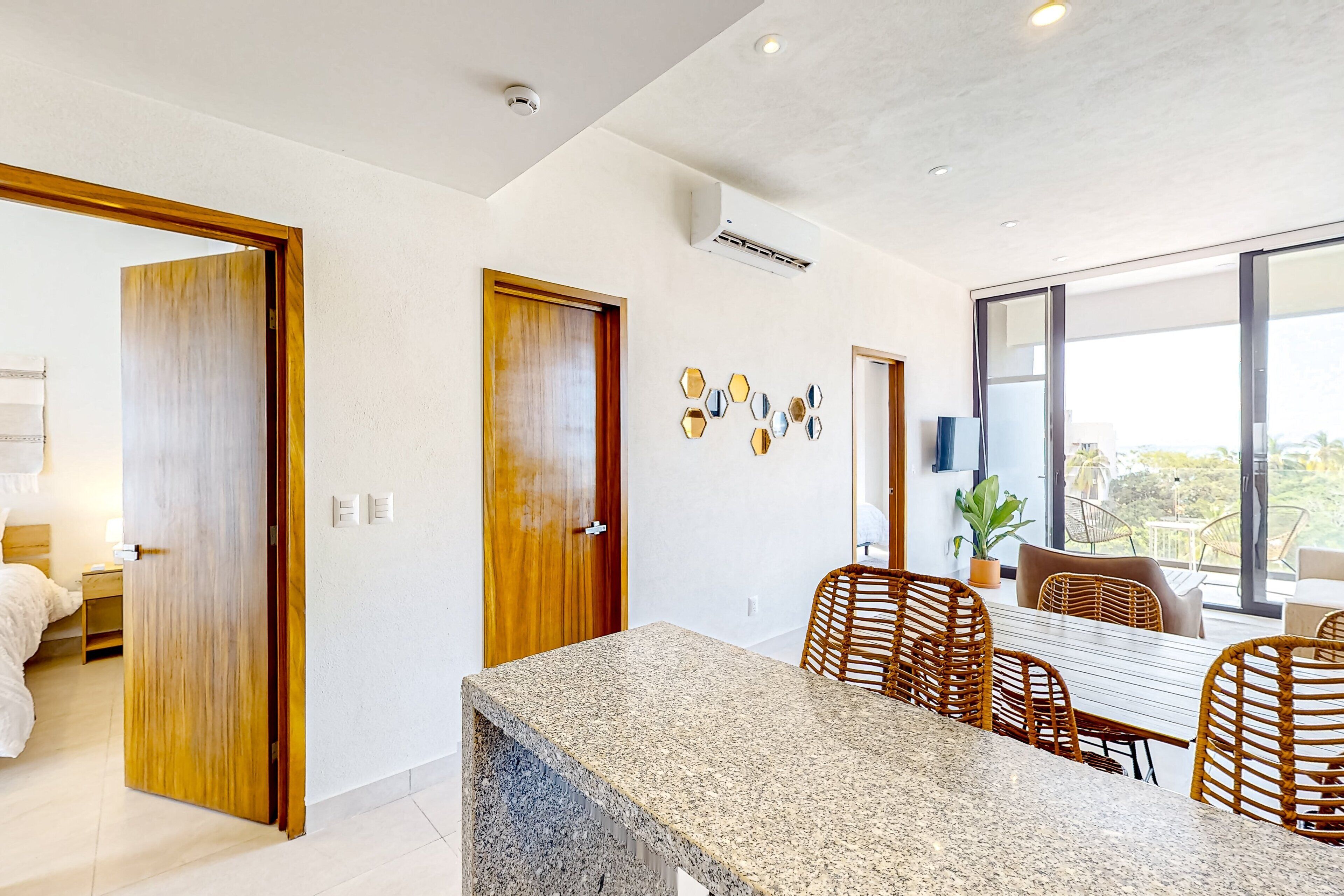 A modern interior with a dining area, wooden doors, and a view through large windows.