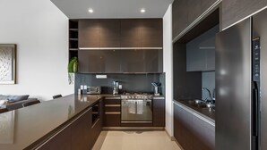 Eine moderne Küche mit dunklen Schränken, einem Edelstahlkühlschrank und einem eingebauten Backofen.