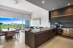 Una cocina moderna con una isla central, electrodomésticos integrados y un comedor con vistas.