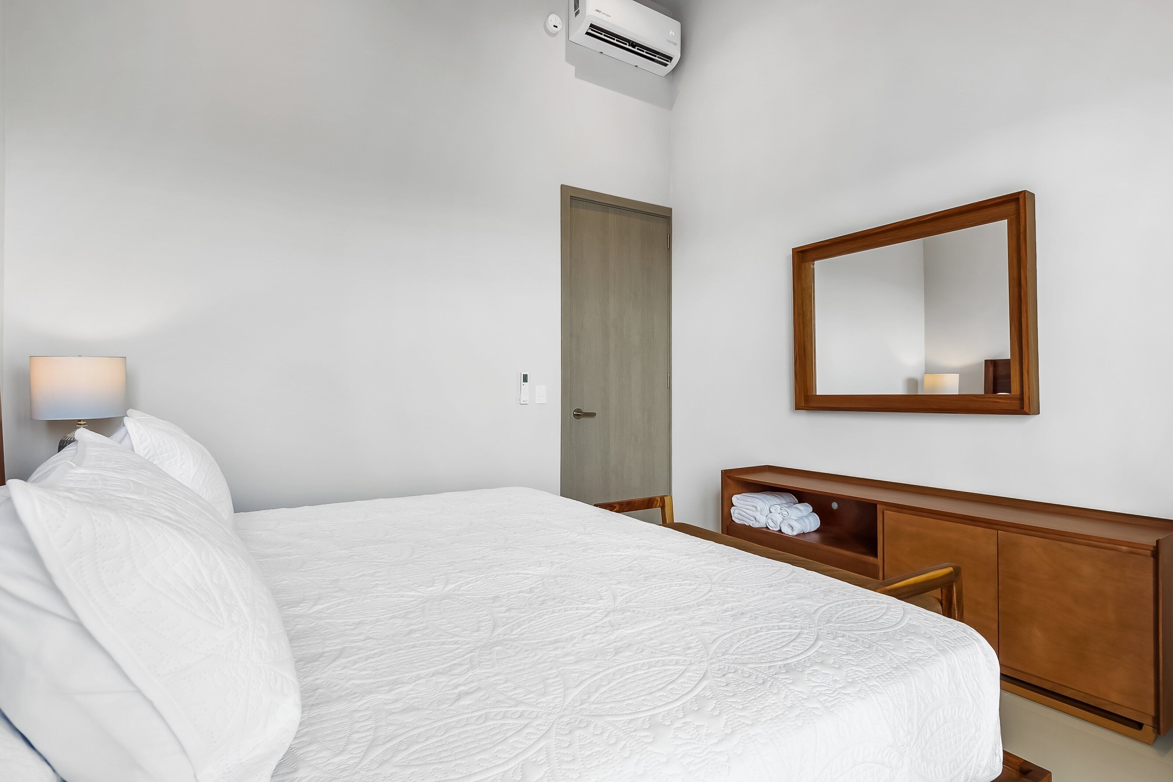 Ein Hotelzimmer mit einem Bett, einem Holzschrank, einem Spiegel und einer Klimaanlage.