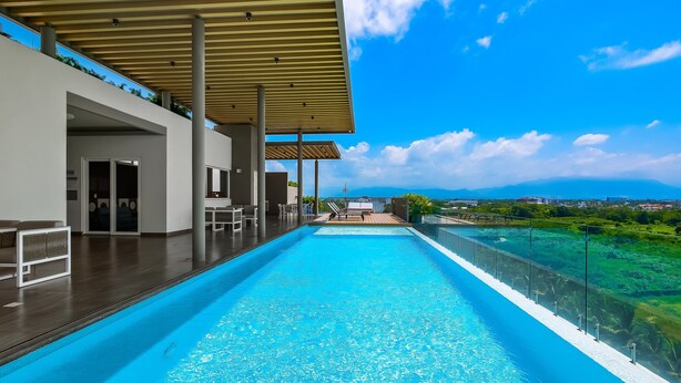 Ein Dachpool mit Infinity-Kante und freiem Blick auf die Landschaft, eine überdachte Sitzgelegenheit und ein modernes architektonisches Design.