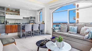 A modern living space with a kitchen, dining area, and a sofa with a view. - Charming Beach Apartment With Pool and Beach Access, Full Kitchen and Wifi (Puerto Vallarta)