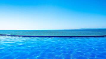 A clear blue pool with a view of the ocean and distant mountains.