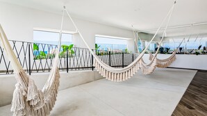 Ein geräumiges Zimmer mit einer Hängematte, großen Fenstern und einem Balkon mit Blick.
