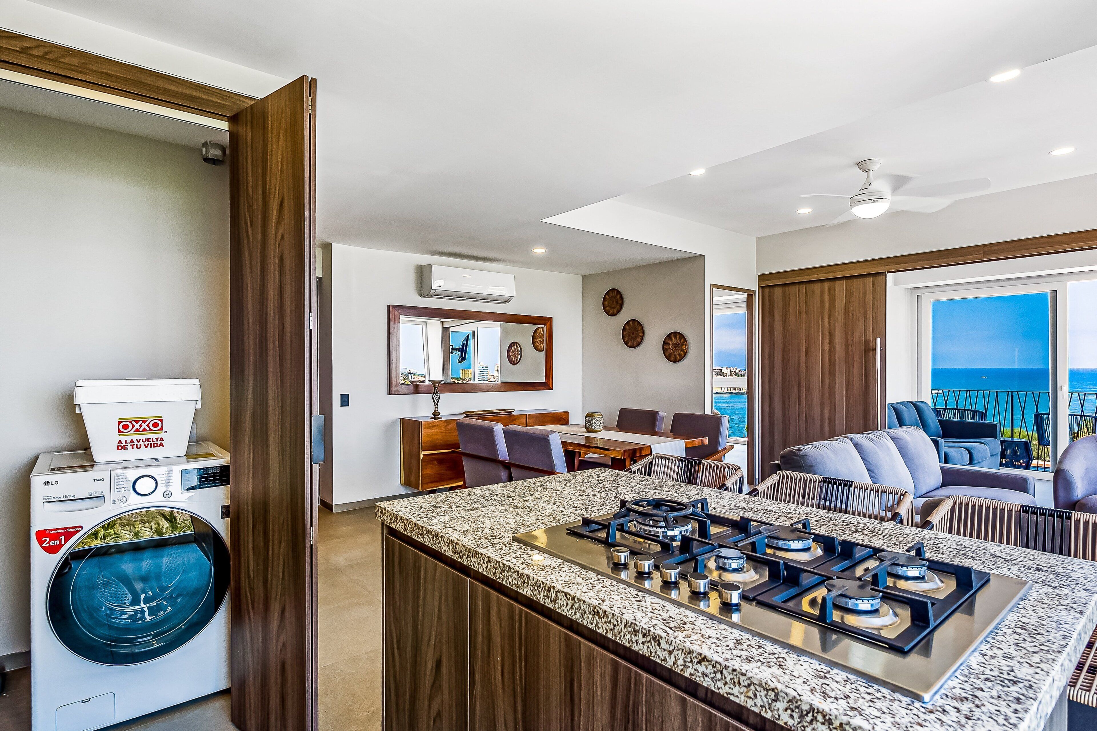 A modern kitchen with a built-in gas stove, a washing machine, and a dining area with a view.