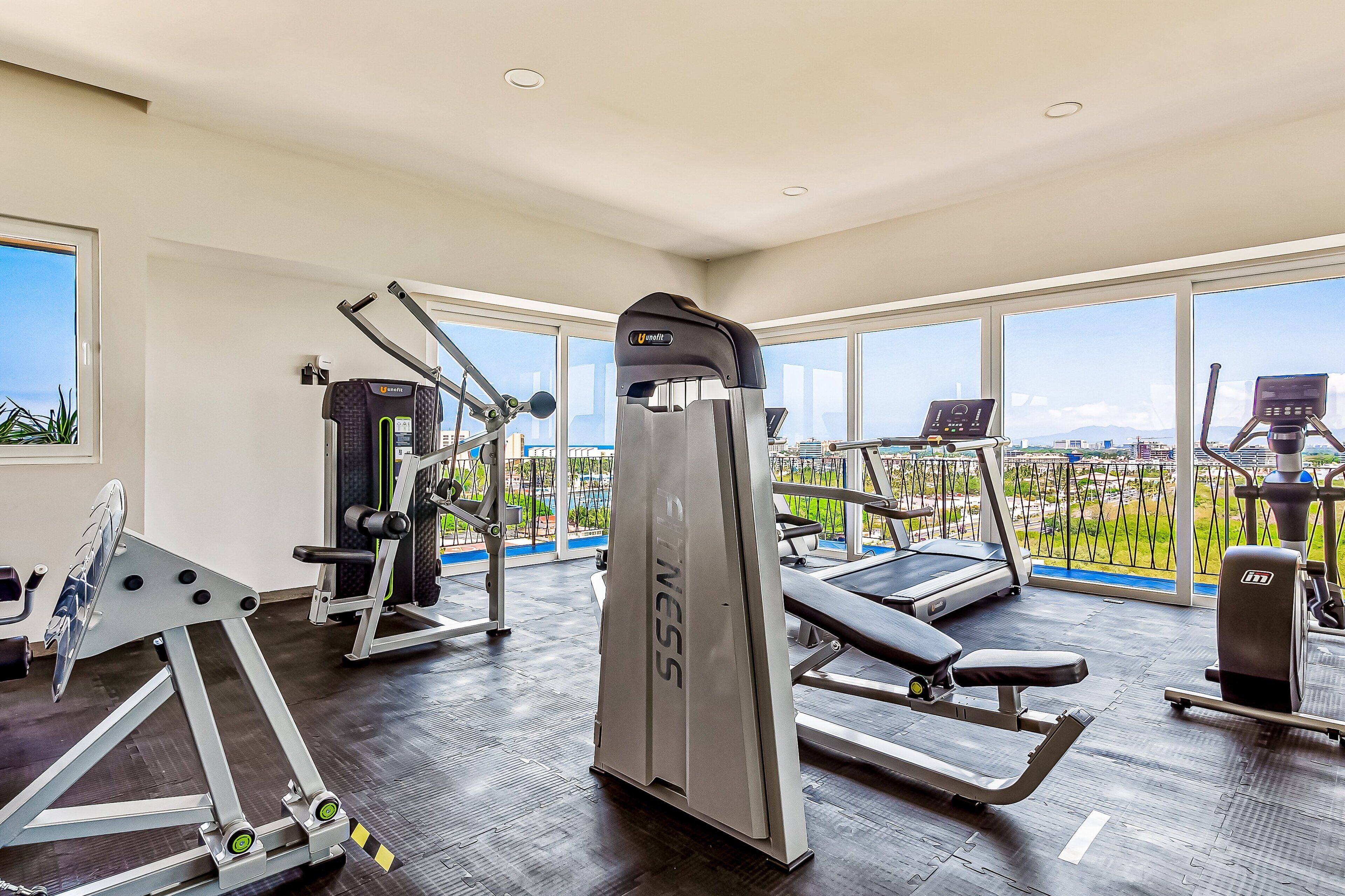 A gym with cardio machines, weightlifting equipment, and a view of the city.