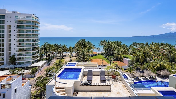 Una terrazza sul tetto di un hotel con piscina, poltrone relax e vista sull'oceano.