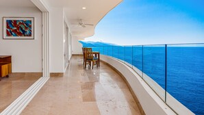 A balcony with a glass railing, a ceiling fan, and a view of the sea. - Luxurious Condo With Huge, Oceanfront Balcony, Pool & Pool spa (Puerto Vallarta)