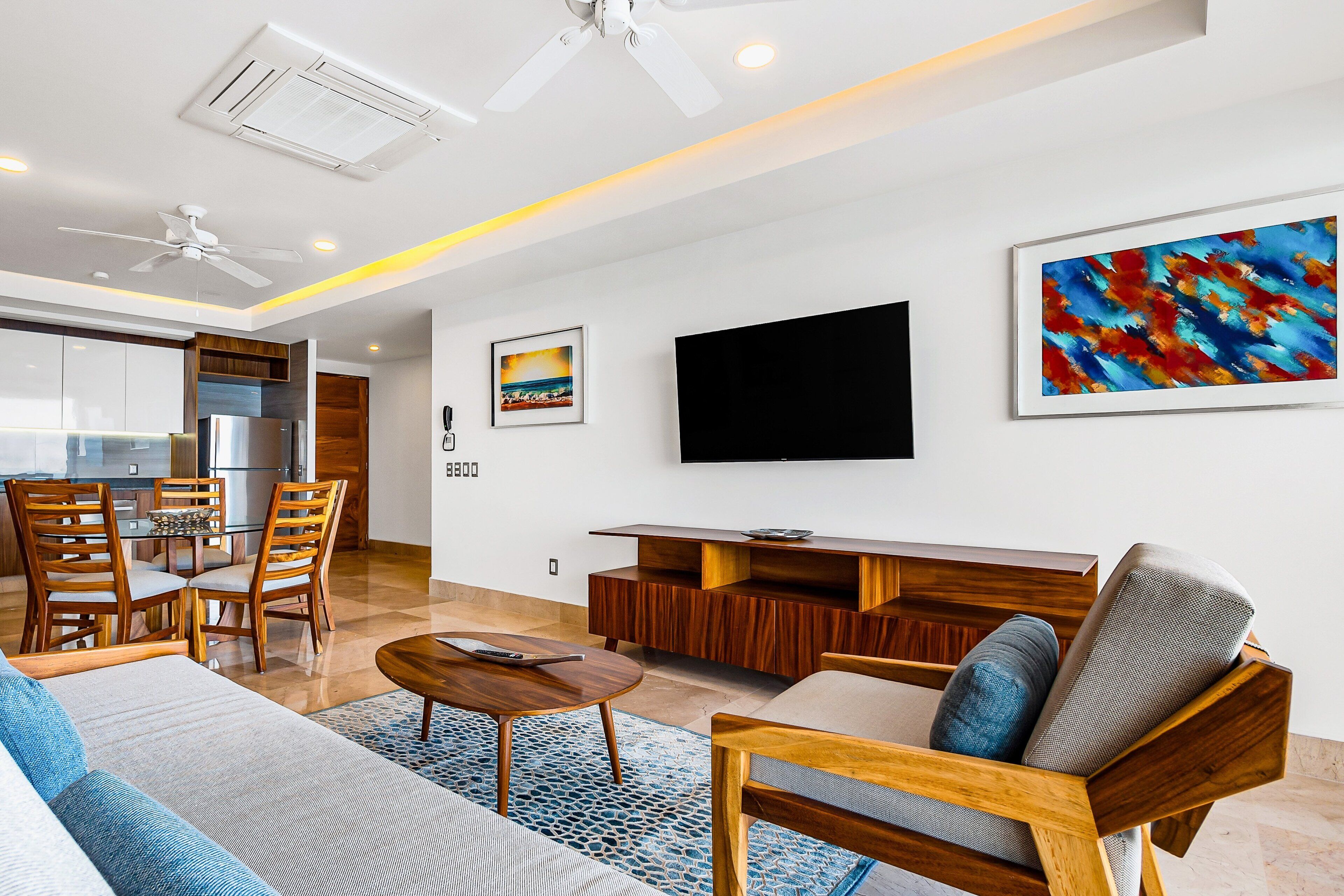 A modern living room with a sofa, coffee table, TV, and artwork on the wall.